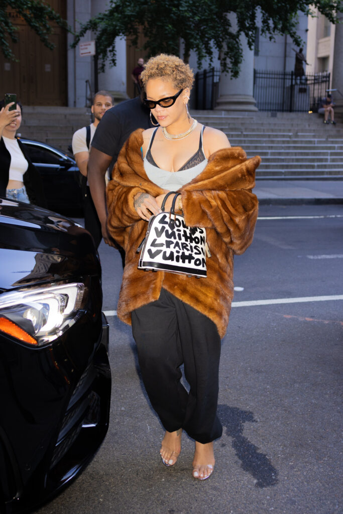 Rihanna was recently seen wearing a large fur coat and using her purse to cover her stomach during a hot New York City day