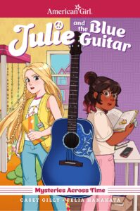Julie and Emma are both shown holding Julie’s diary with a blue guitar between them.