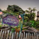 The sign for Tiana’s Bayou Adventure at dusk