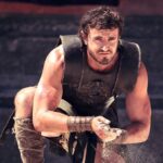 Paul Mescal as a Gladiator rubbing sand in his hands as he kneels near his sword in Gladiator 2