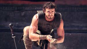 Paul Mescal as a Gladiator rubbing sand in his hands as he kneels near his sword in Gladiator 2