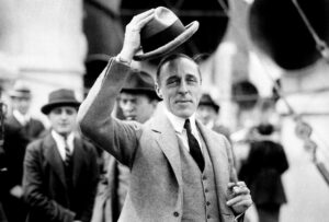 D.W. Griffith, facing the camera, lifts his hat from his head