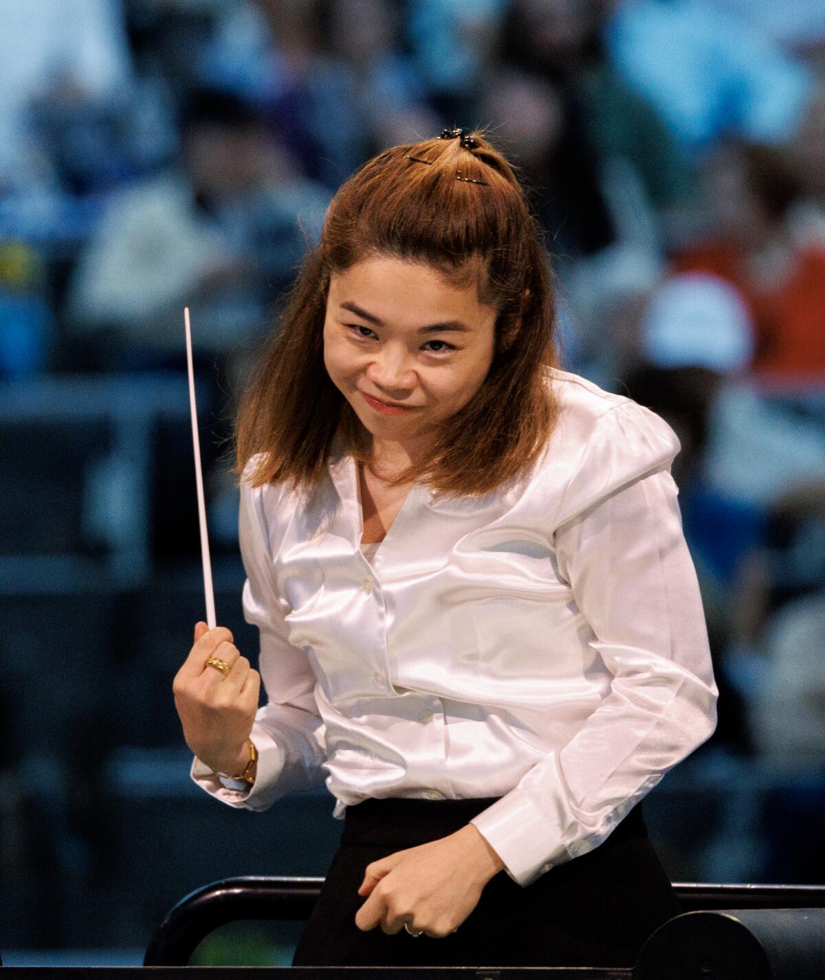 Elim Chan points her baton up with a wry smile at the musicians.