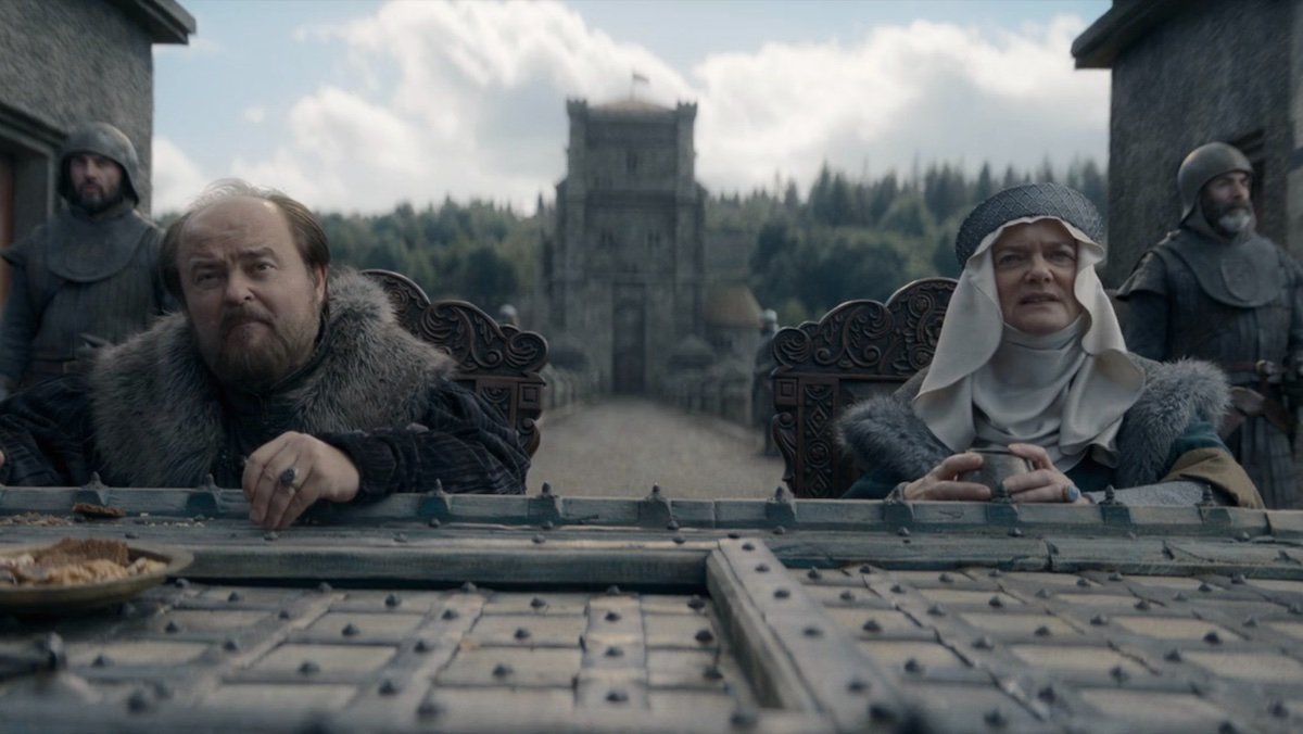 Lord and Lady Frey sit on their bridge at the Twins with guards behind them on House of the Dragon