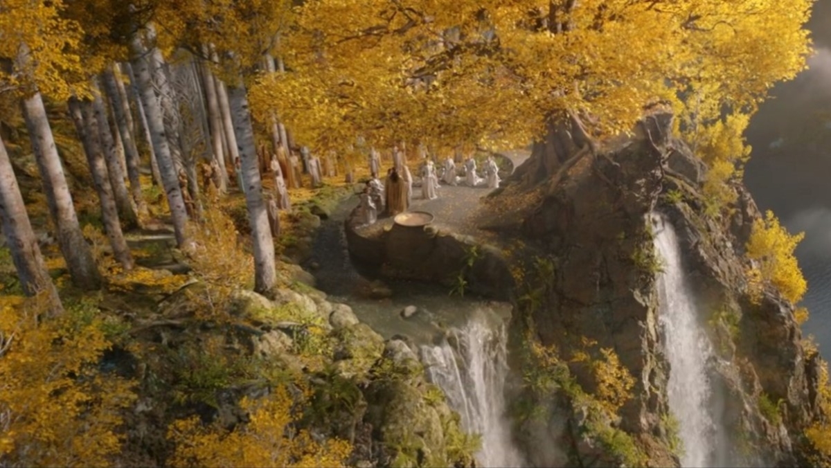 Trees with yellow leaves and a group of elves stand above a waterfall in The Rings of Power