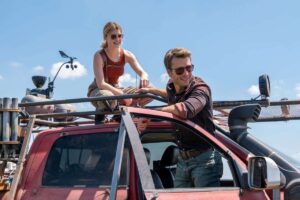 A woman on top of a truck and a man in sunglasses prepare to chase the storm.
