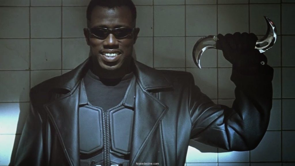 Wesley Snipes, wearing sunglasses, smiles while holding a blade