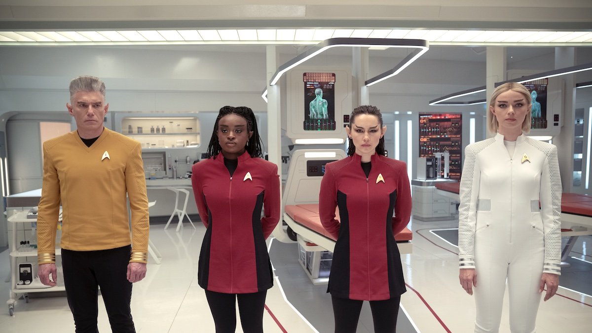 Human characters turned into Vulcans standing in their Starfleet uniforms in a brightly lit hospital bay on Star Trek: Strange New Worlds