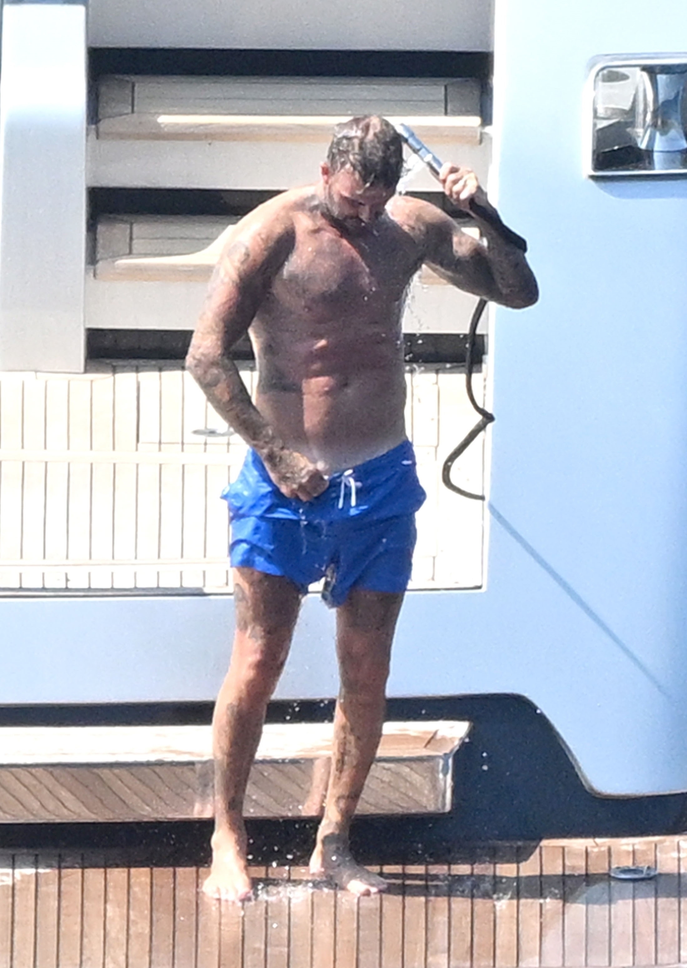 David pulled his blue swimming shorts up high to expose his impressive thigh tattoos before hitting the shower