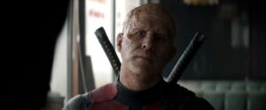 Wade Wilson (Ryan Reynolds), in the Deadpool costume and weapons but without his mask, looks serious in Deadpool & Wolverine
