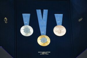 This photograph taken in Paris on February 8, 2024, shows the Olympic medals during the unveiling of the Olympic and Paralympic medals for the Paris 2024 Olympic Games. On the medals' head side, the engraved figures of the goddess of victory Athena, Nike, the Panathenaic stadium, and the Acropolis are imposed by the International Olympic Committee (IOC). Still, Paris 2024 has obtained exceptional authorization to add the design of the Eiffel Tower and use 18 grams of Eiffel Tower metal on each medal, extracted from pieces of the tower. (Photo by Dimitar DILKOFF / AFP) (Photo by DIMITAR DILKOFF/AFP via Getty Images)