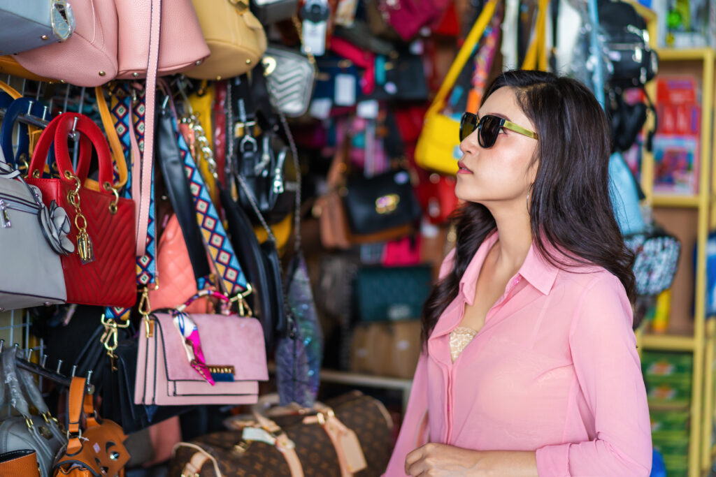 young woman choosing and shopping handbag in store
