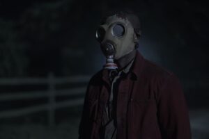 A person with a gas mask standing in a dark road in Peacock’s Teacup