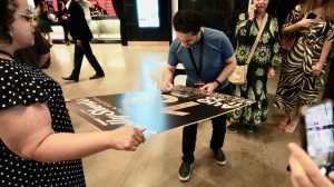 Actor-producer Mehrdad Sarlak signs a poster at the HollyShorts Film Festival.
