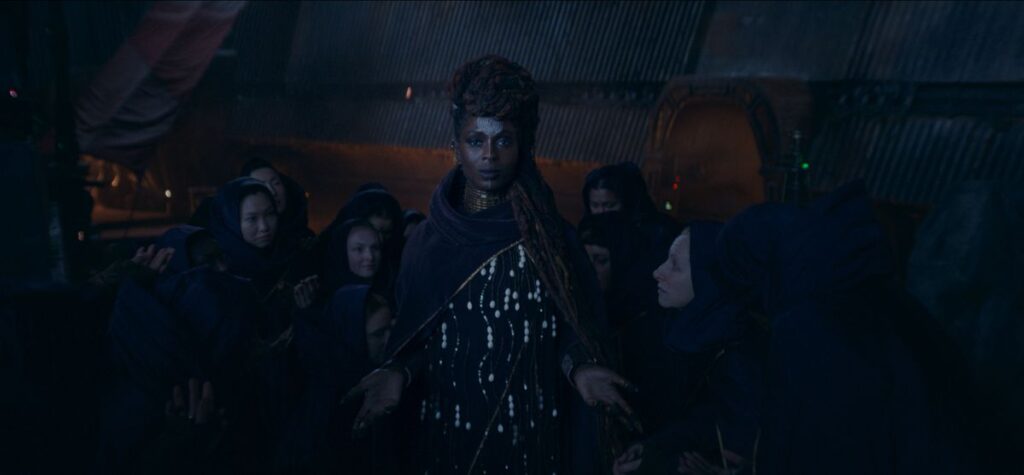 Jodie Turner-Smith as Mother Aniseya in Star Wars: The Acolyte, shielding several people behind her