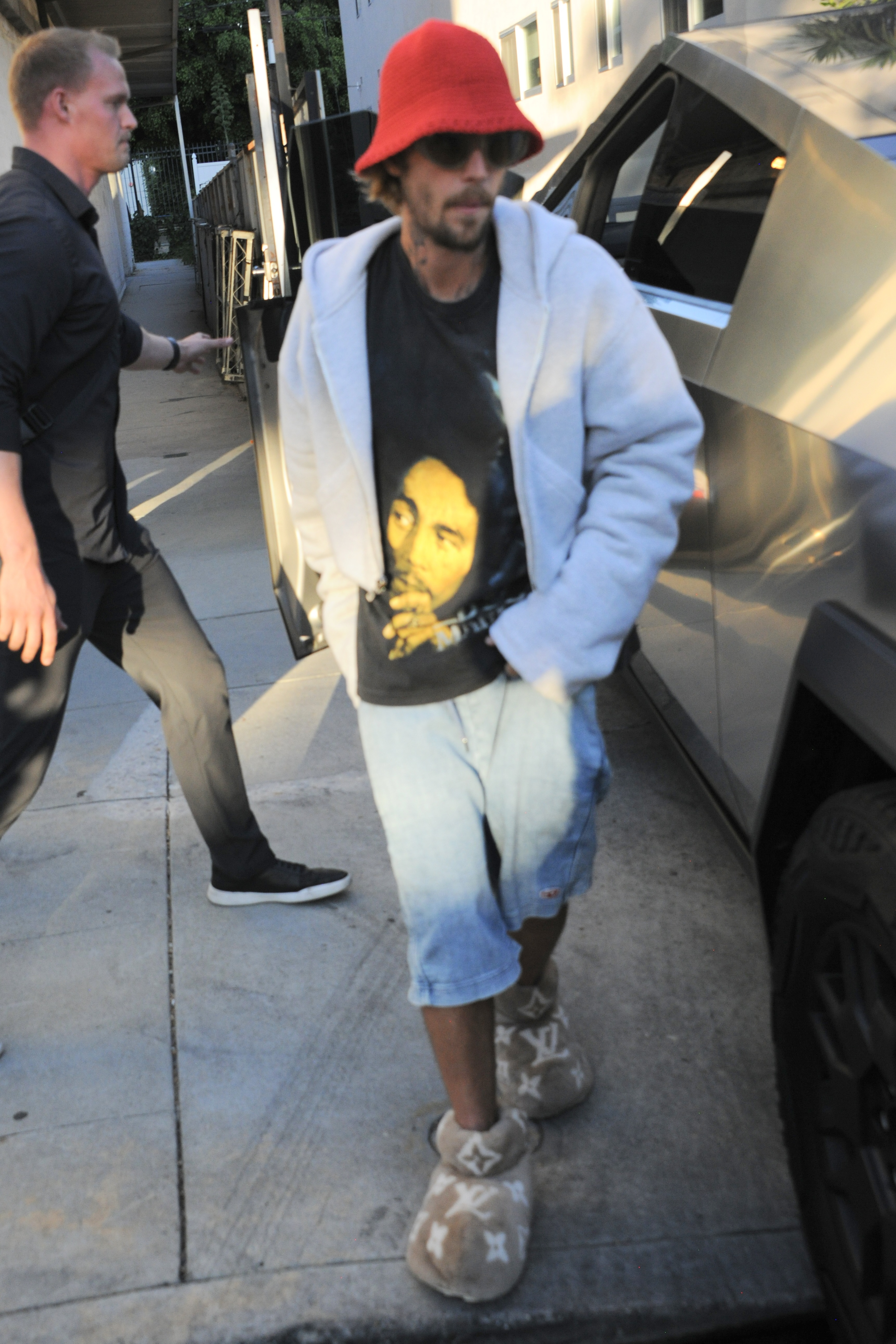 The Baby singer paired the beige shoes with a Bob Marley t-shirt, denim shorts, and a red bucket hat.