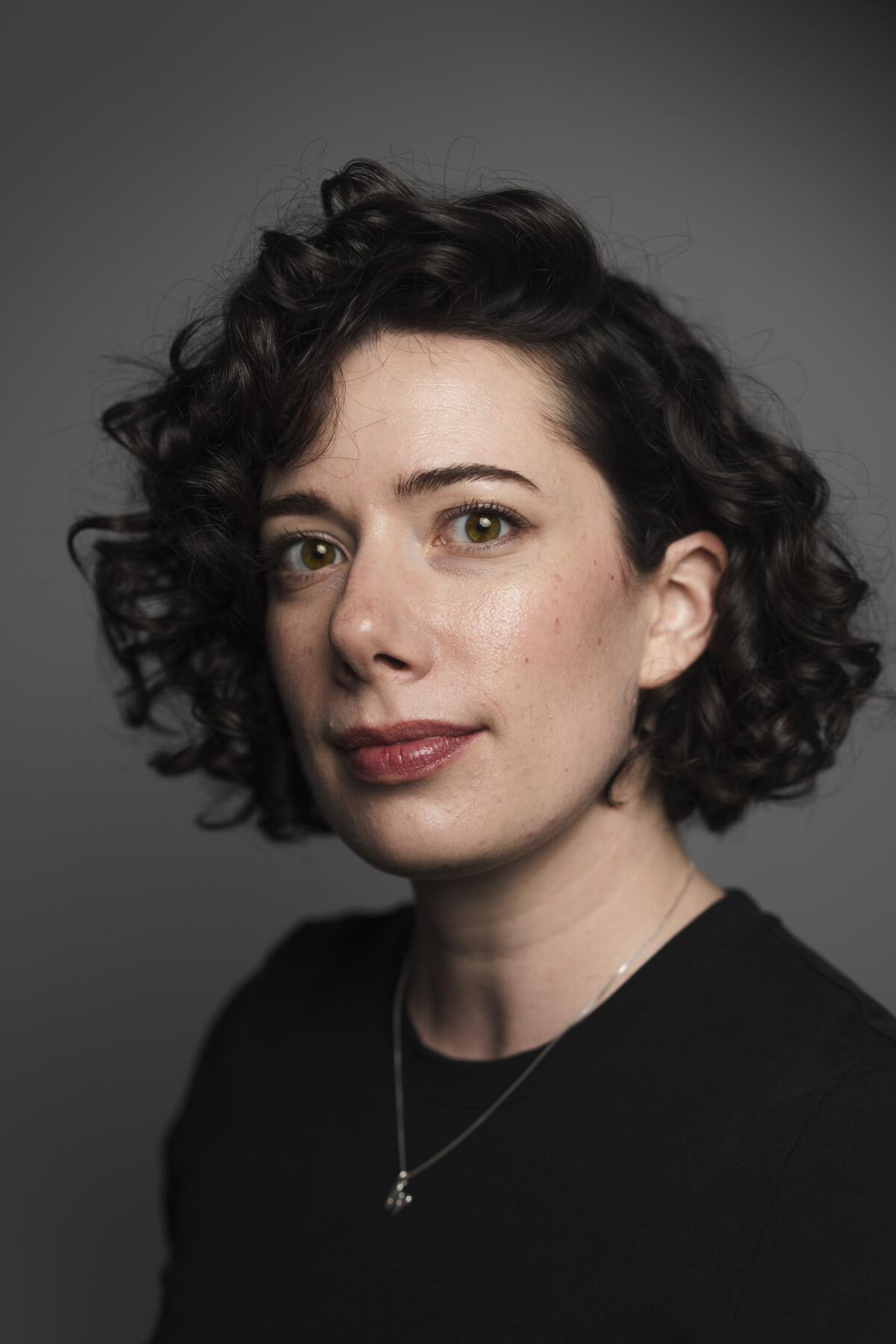 A woman with dark curly hair in a black shirt