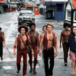 Shirtless gang members in vests walk the streets of New York in "The Warriors."