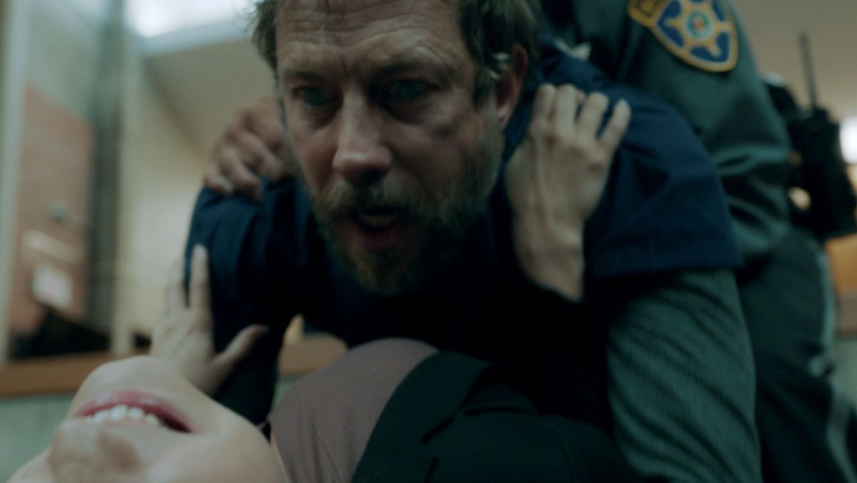 Believer trailer featuring a man jumping on a woman while an officer tries to hold him back