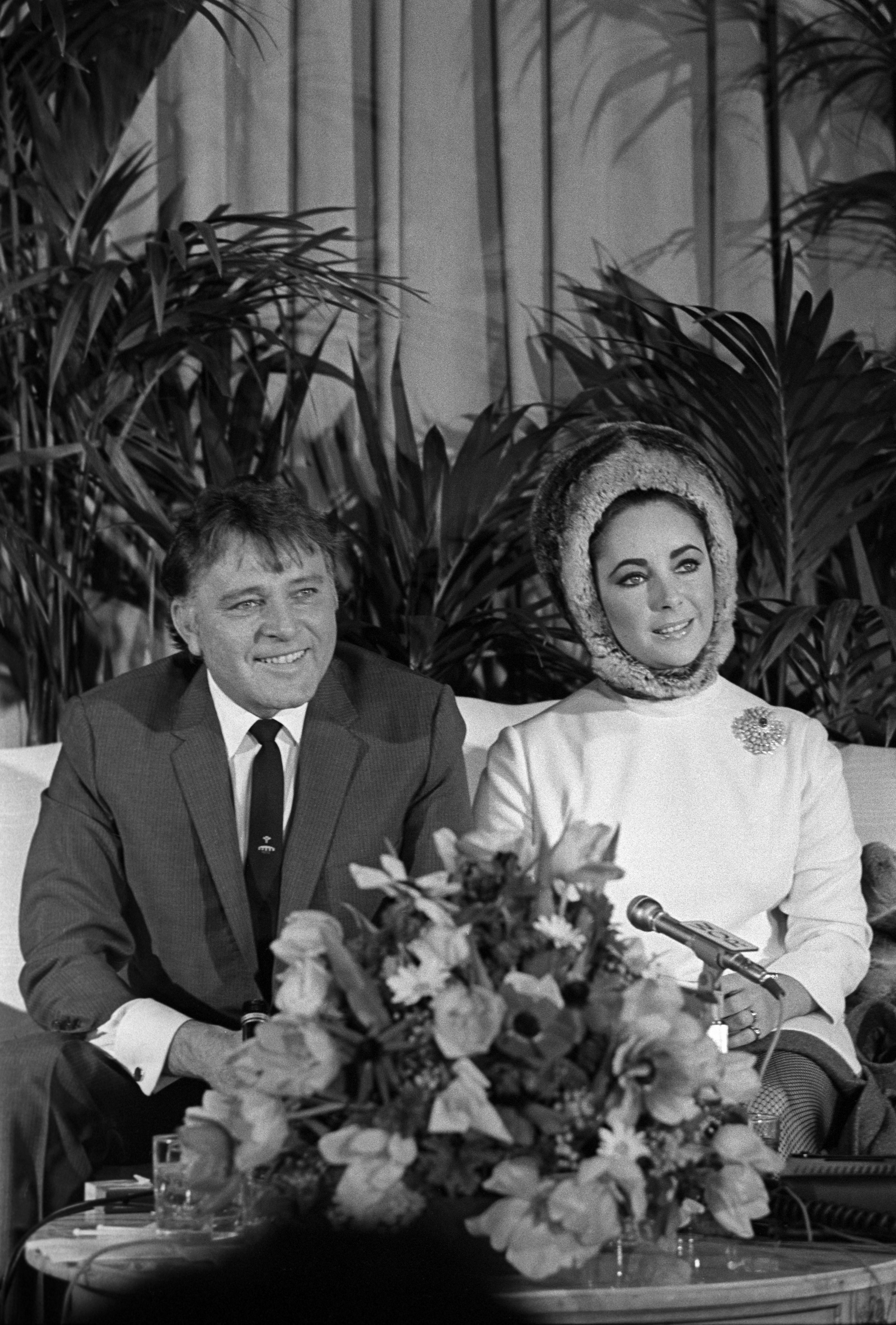 Elizabeth Taylor wearing a fur hat at a press conference with husband Richard Burton