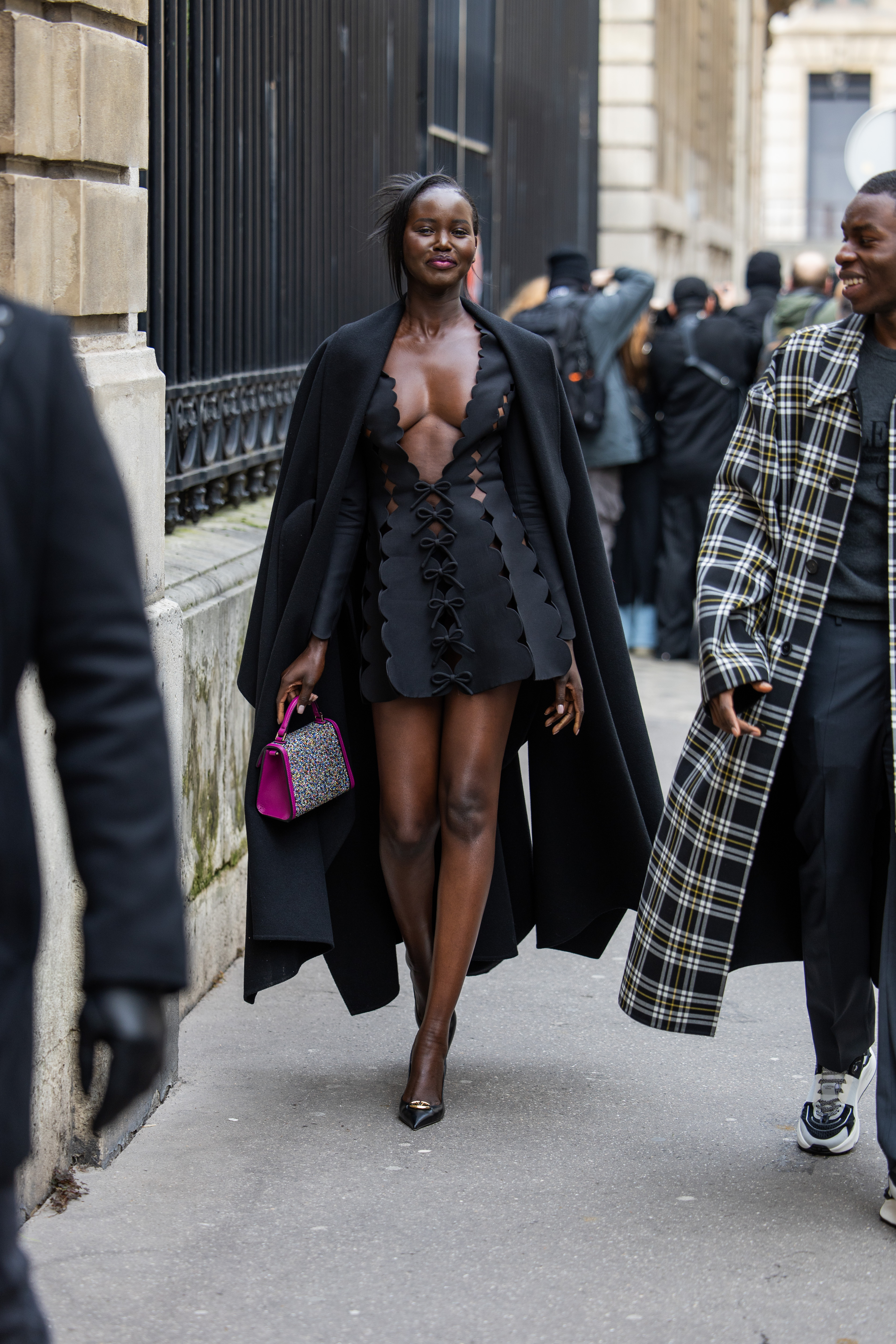 Adut Akech wears a black cut-out dress and long coat while attending Paris Fashion Week on March 3