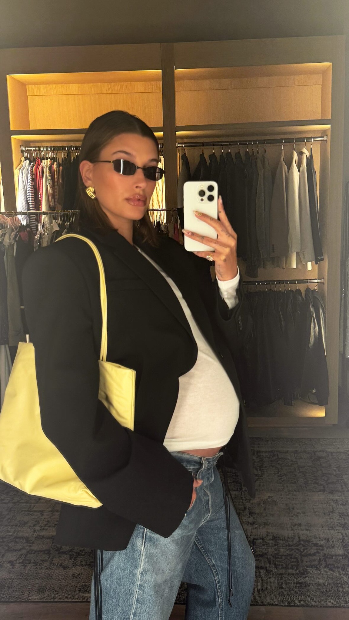 Hailey Bieber shows off her baby bump in a form-fitting white top and low-rise jeans