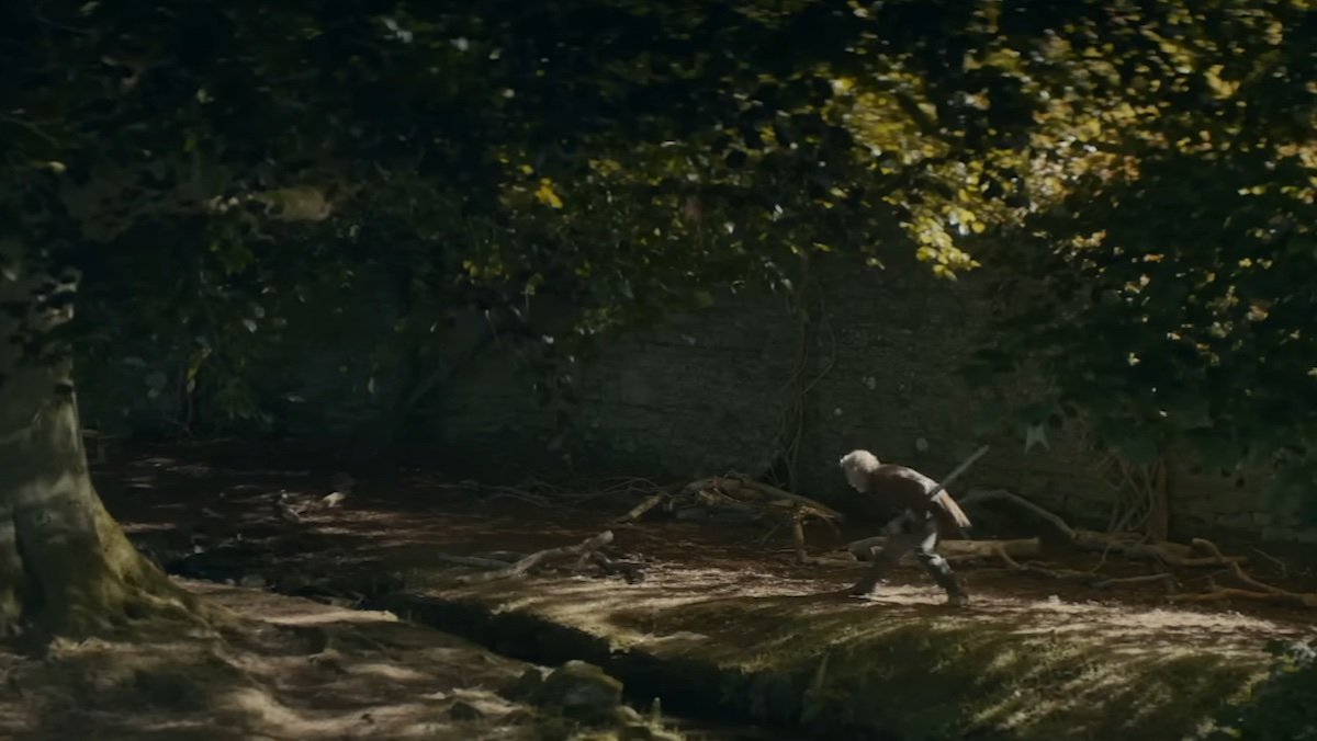 An older knight practices with his sword near a tree in the woods on A Knight of the Seven Kingdoms