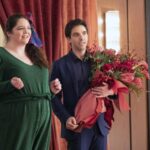 A man carrying a large bouquet of flowers stands with a smiling woman in "Hacks."