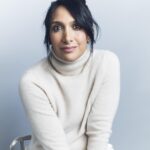 a woman wearing an off-white turtleneck sweater sitting in a chair