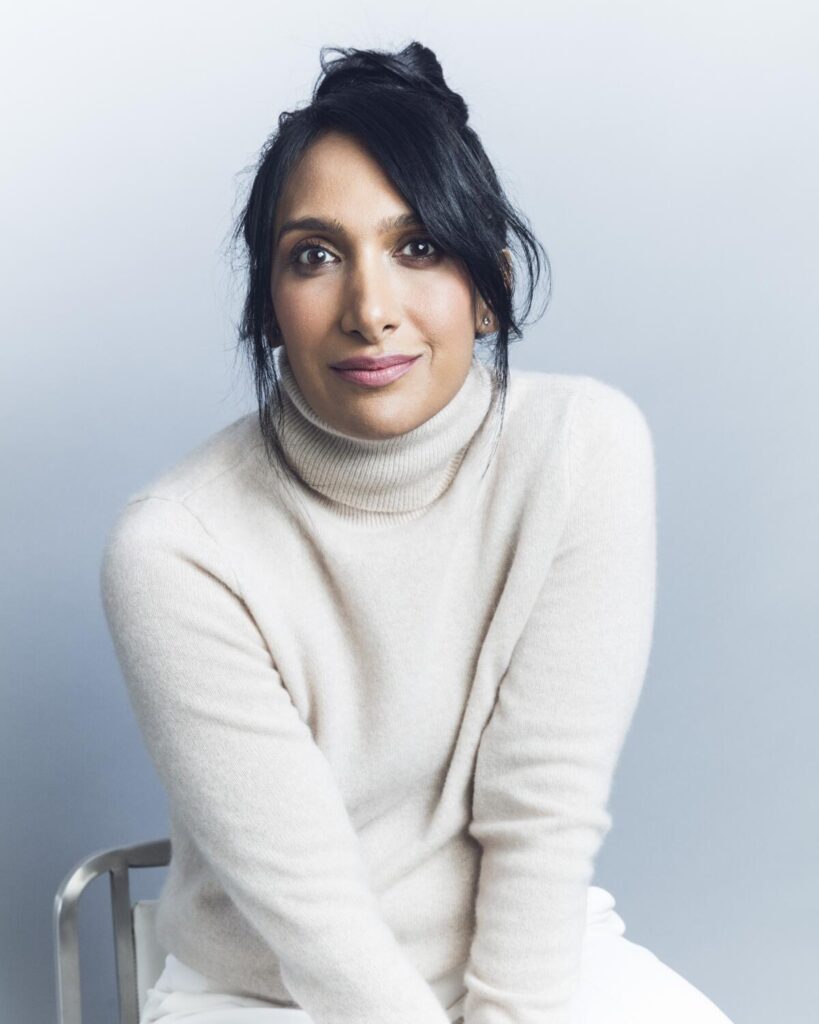 a woman wearing an off-white turtleneck sweater sitting in a chair