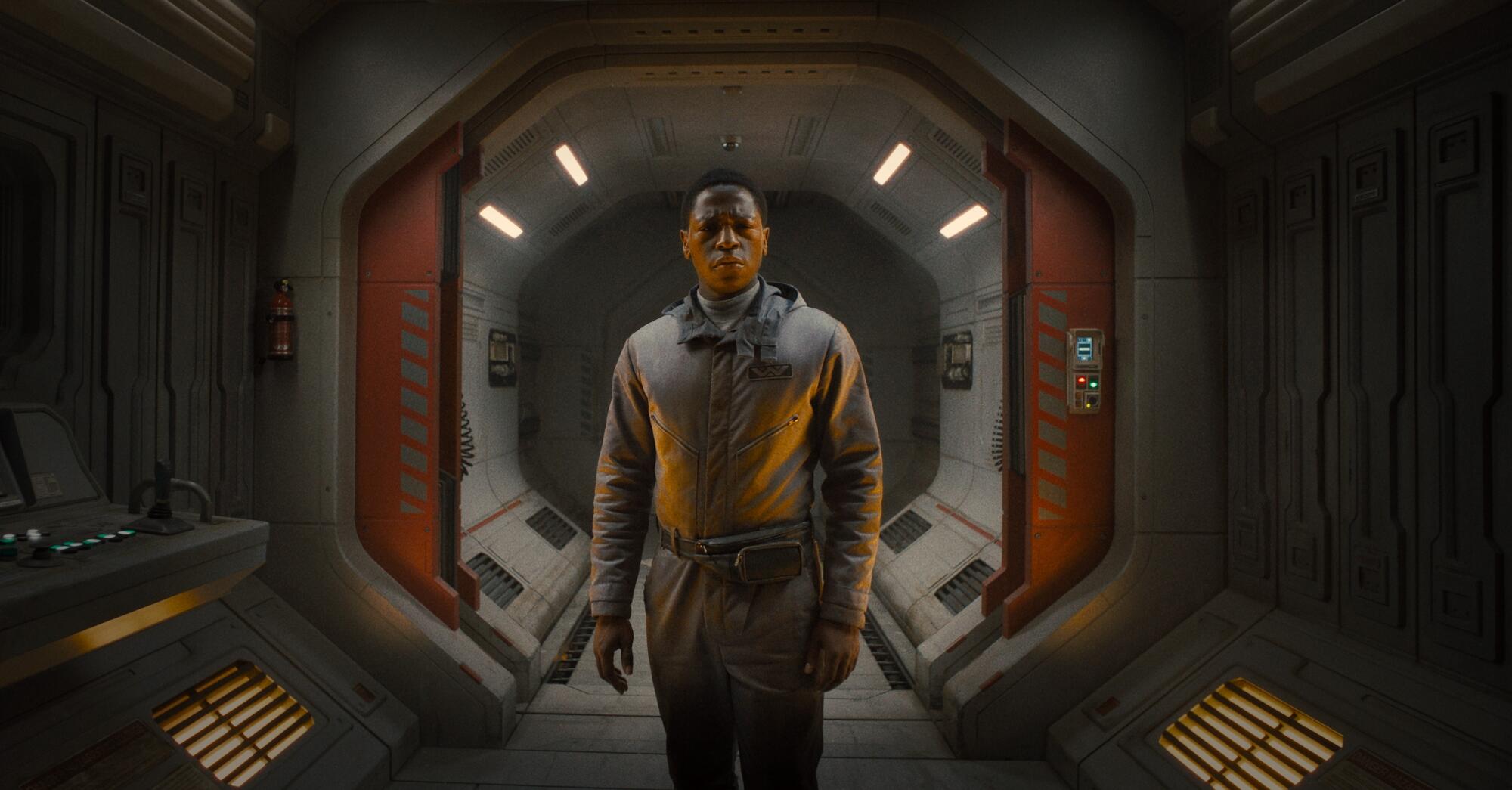 A man stands in a spaceship corridor.