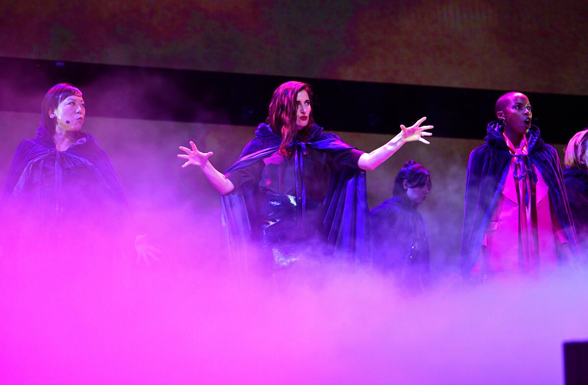 four people wearing cloaks on a foggy stage