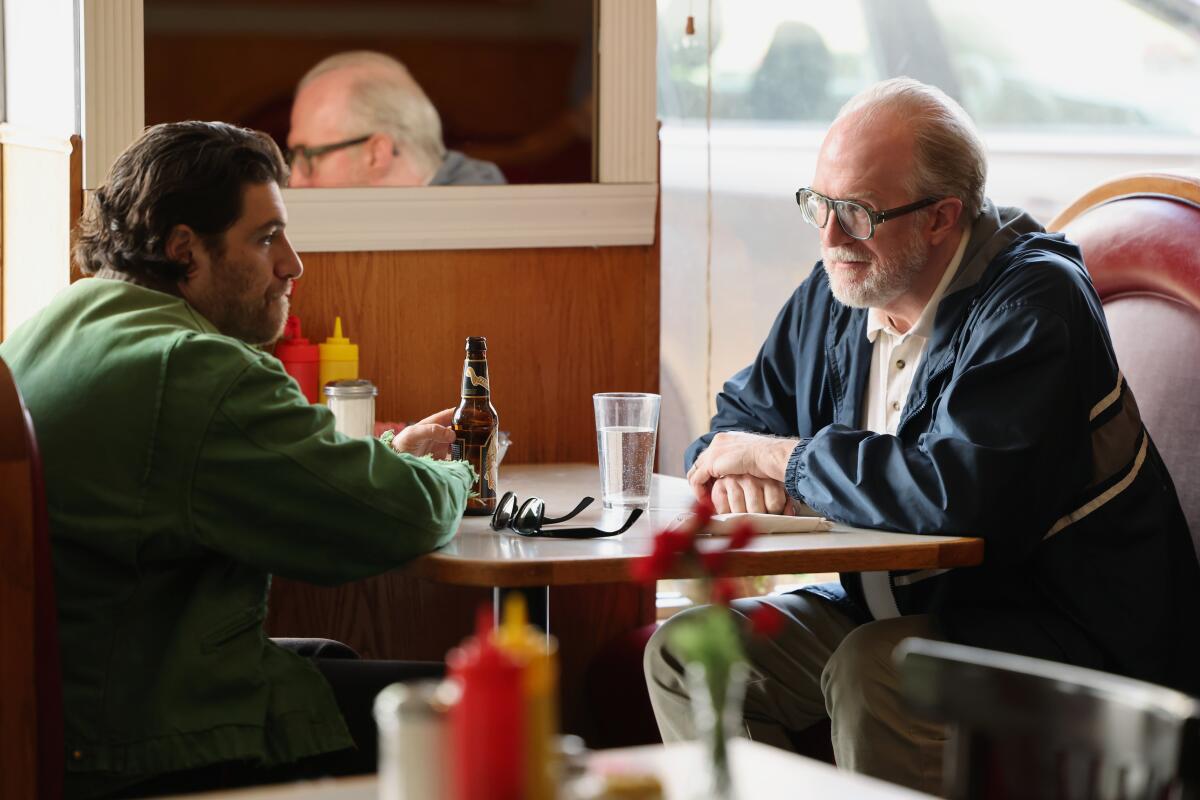 Two men sit in a booth at a diner.