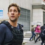 John Krasinski looks up as people run away behind him in Jack Ryan