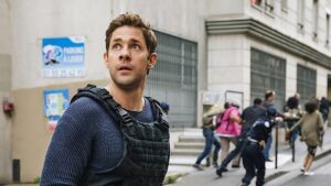 John Krasinski looks up as people run away behind him in Jack Ryan