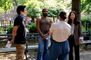 Director Hiro Murai talks with actors Donald Glover and Maya Erskine and a woman with her back to the camera.