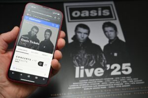 A fan uses a smartphone to access an online ticket sales website to purchase tickets for Oasis'