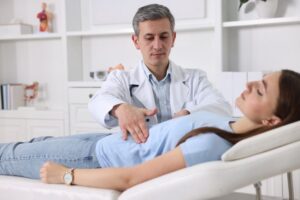 Male gastroenterologist examining young female patient with stomach pain