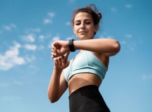 Woman in workout clothes looking at her watch.