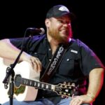 Luke Combs on stage with his guitar.