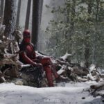 Deadpool (Ryan Reynolds) sits on a fallen tree in a snowy forest next to the rotted corpse of Wolverine (Hugh Jackman) in Deadpool & Wolverine