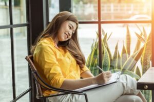 woman taking notes while speaking with a reference