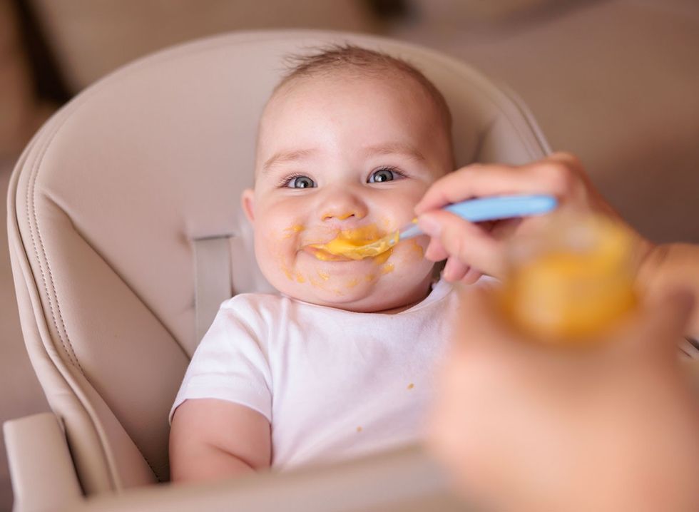 A happy baby eating baby food