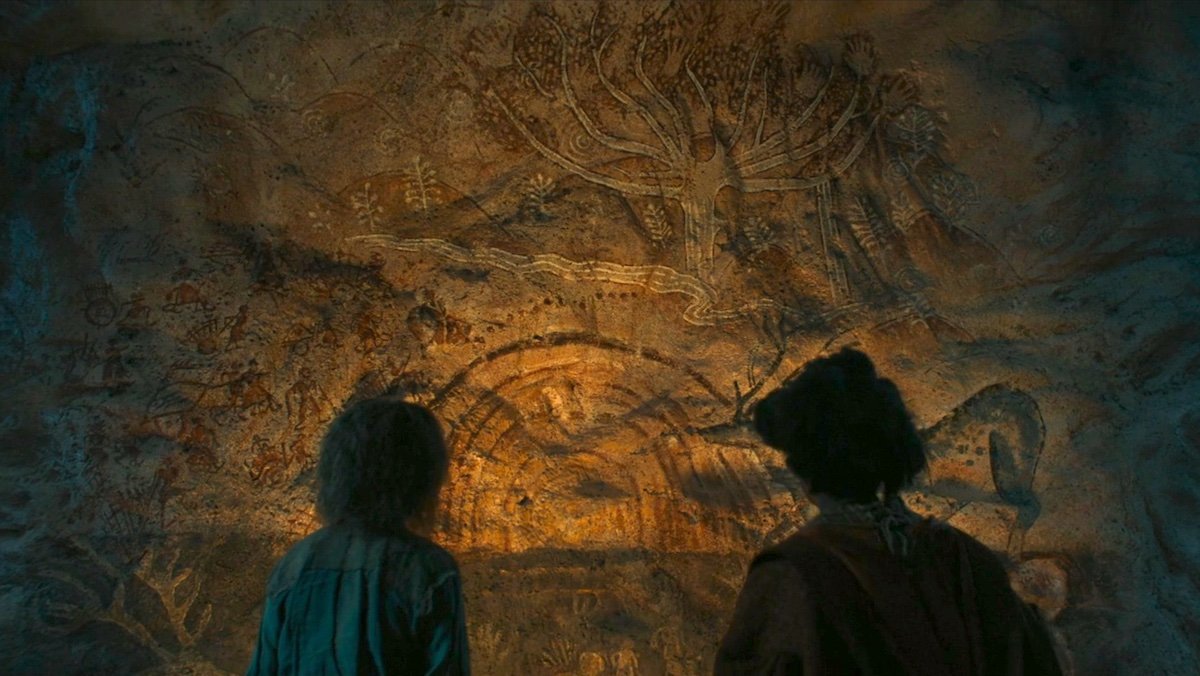 Nori and The Gund look at a painting on a stone wall on The Rings of Power