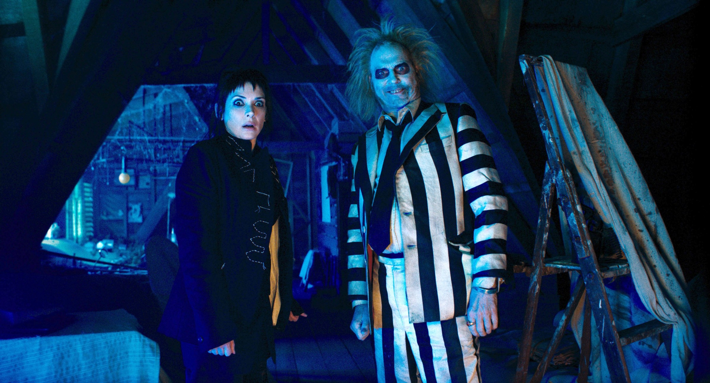 Lydia Deetz (Winona Ryder) and Betelgeuse (Michael Keaton) stand side by side in Beetlejuice Beetlejuice