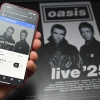 A fan uses a smartphone to access an online ticket sales website to purchase tickets for Oasis' 