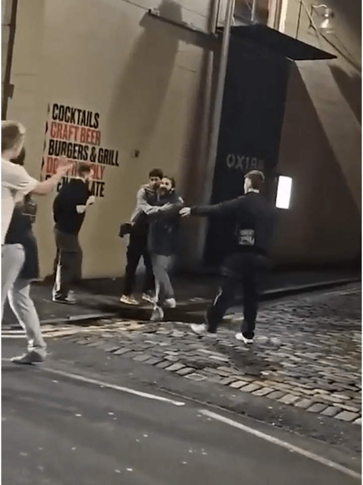 LaBeouf is seen being held back while a man gestures at him