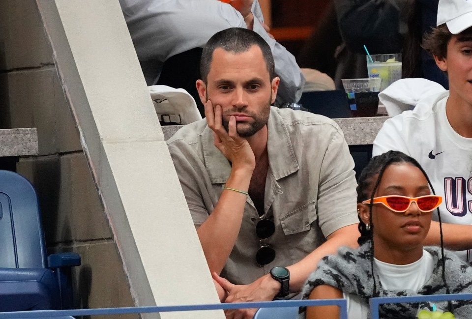 Penn Badgley sits with his head in his hand at the 2024 US Open while debuting a brand new hairstyle