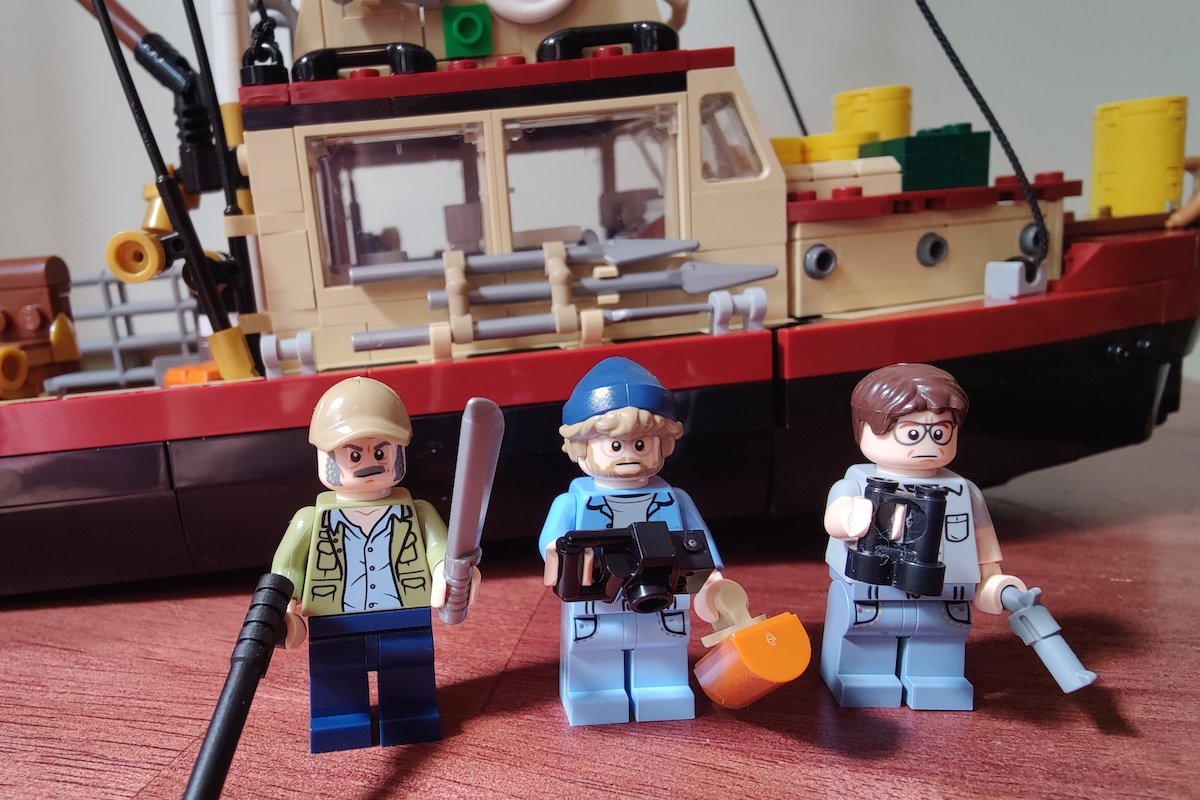 Minifigures of Quint, Hooper, and Brody standing in front of the Orca from the LEGO Jaws Set