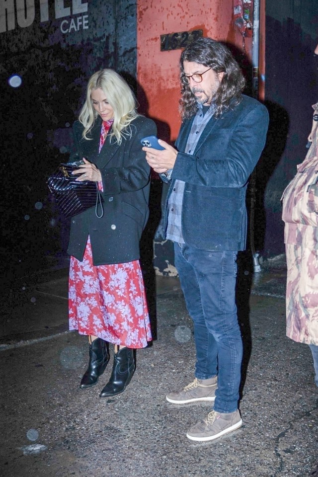 Foo Fighters singer Dave Grohl looks at his phone while his wife, Jordyn Blum, digs through her purse outside a comedy club in Los Angeles, California